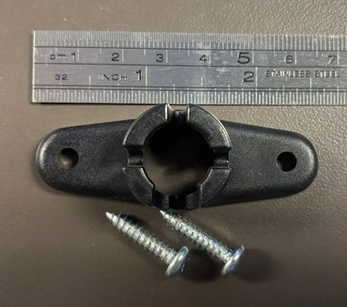 A black metal bracket with a hole in the center and two screws placed next to it, with a ruler for scale in the background.