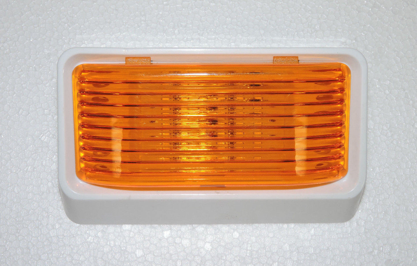 Optronics RV porch light with amber lens and white housing