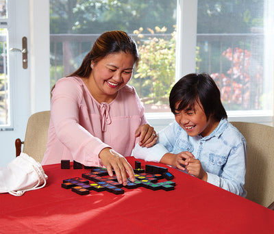 Qwirkle game set with wooden tiles played by mother and child