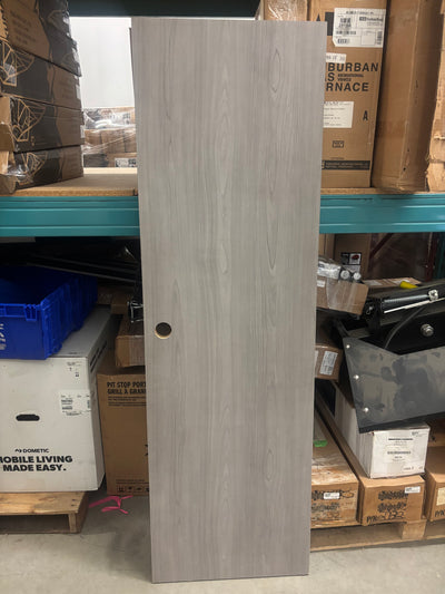 A silverton maple cabinet door standing upright on a shelf with various items in the background.