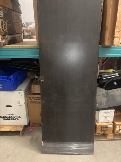 A dark brown wooden door leaning against a wall, with packaging and boxes around it, indicating it is stored or being sold in a retail setting.
