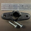 A black metal bracket with a hole in the center and two screws placed next to it, with a ruler for scale in the background.
