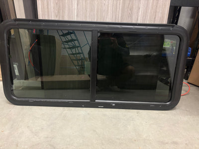 A black RV full exit window with visible glass and black frame, installed in an RV.