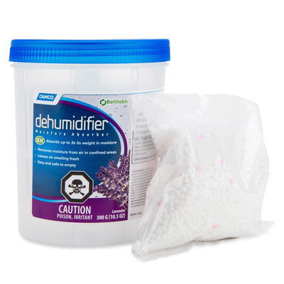 A white plastic tub of CAMCO Dehumidifier 3X with a blue lid and purple label, shown next to a clear plastic bag filled with white desiccant granules on a white background.
