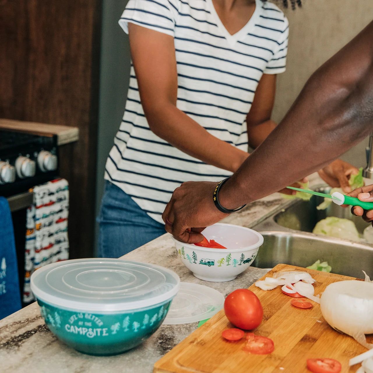 Two people preparing food in a kitchen with a focus on a teal container labeled 'Camperite'.
