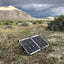 Solar panels on the ground in a desert landscape with mountains in the background