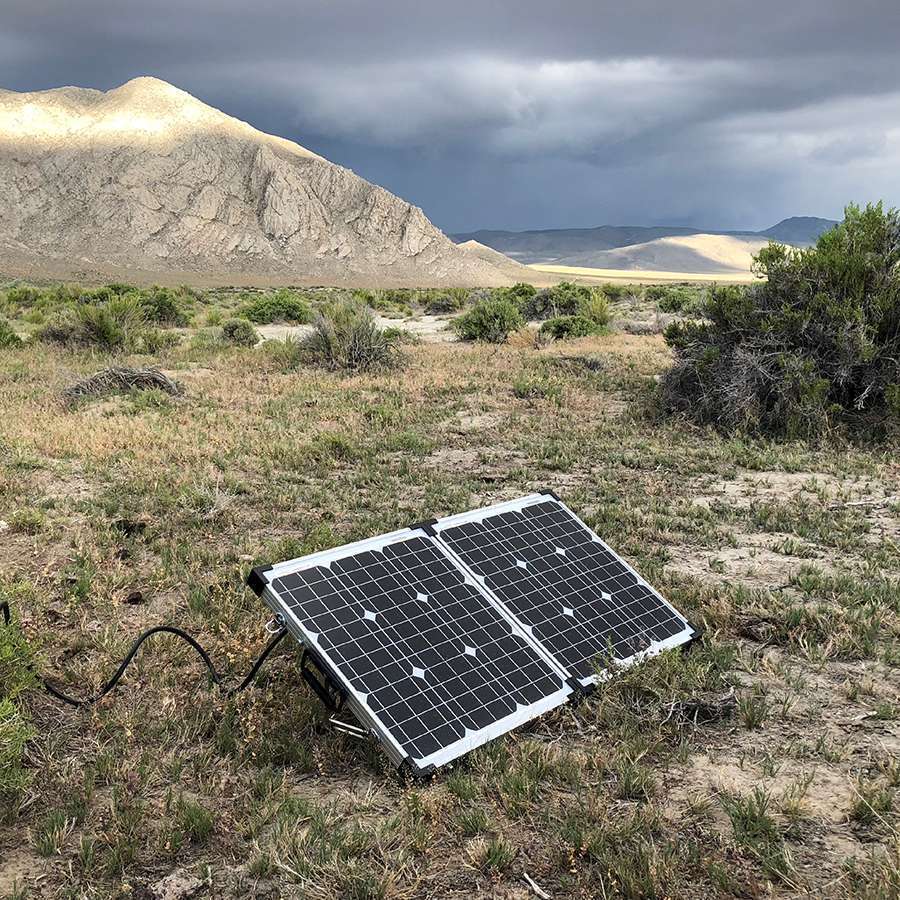 Solar panels on the ground in a desert landscape with mountains in the background