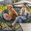 Woman with a dog sitting on a camping chair in a natural setting