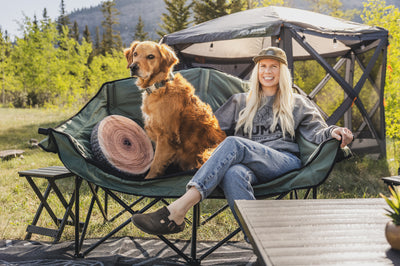 Woman with a dog sitting on a camping chair in a natural setting