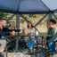Group of people sitting around a table in a geodesic dome tent outdoors.