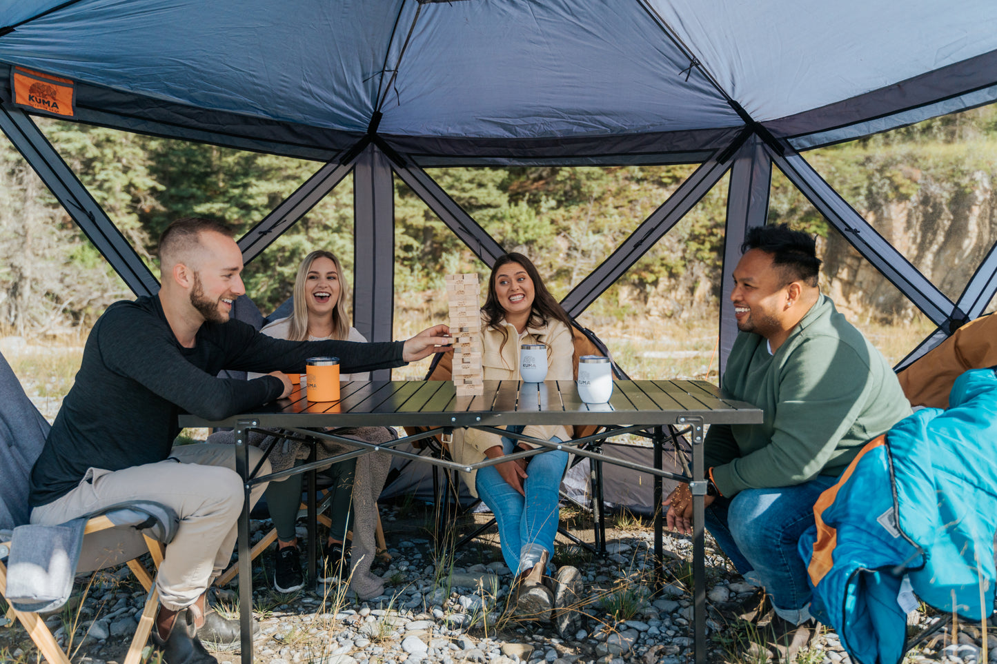 Group of people sitting around a table in a geodesic dome tent outdoors.