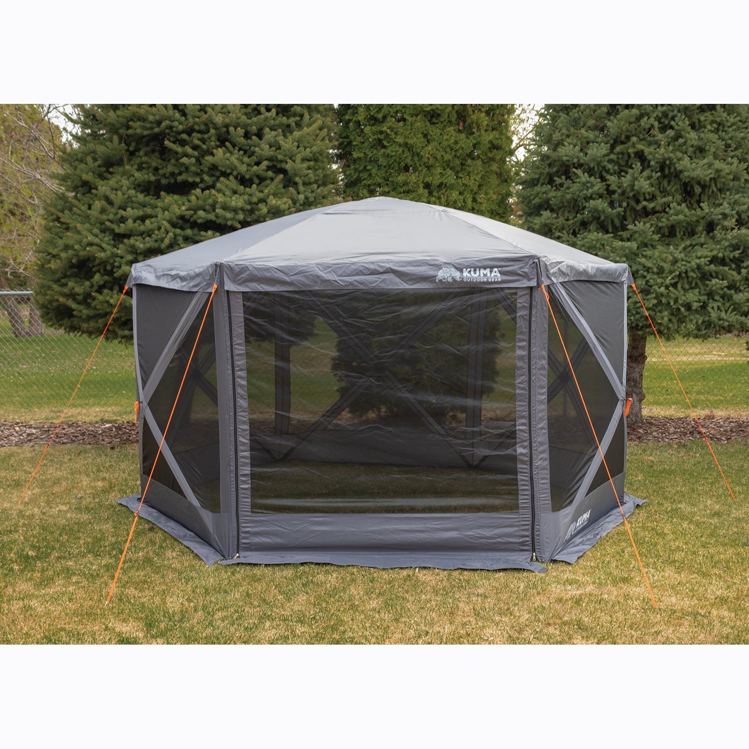 Outdoor screen tent set up on grass with trees in the background