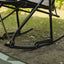 Close-up of a black metal chair with a blurred natural background