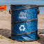 Blue recycling bin with Kuma Outdoor Gear logo on a beach