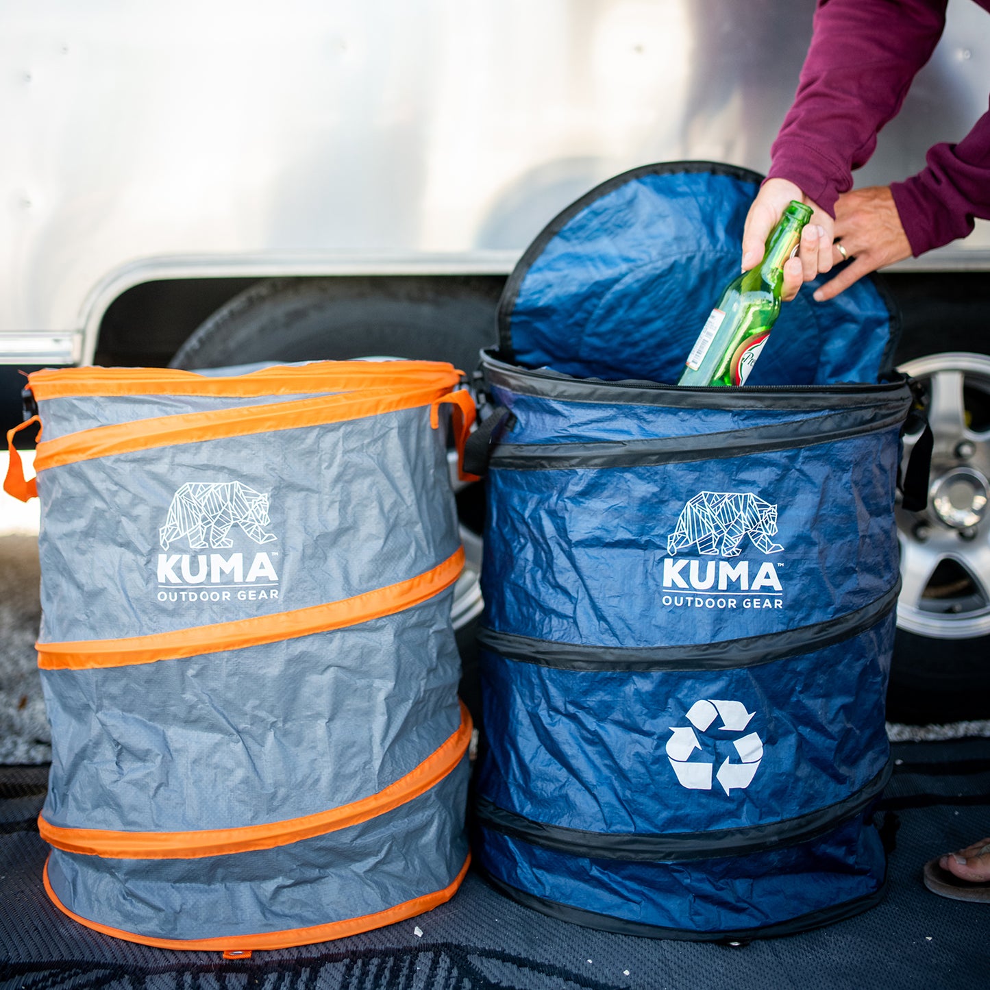 Kuma outdoor gear collapsible trash can and recycling bin with a person placing a bottle inside.