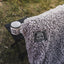 Gray sherpa blanket with Kuma Outdoor Gear logo on a grassy background
