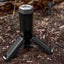 Black flashlight with tripod stand on a forest floor