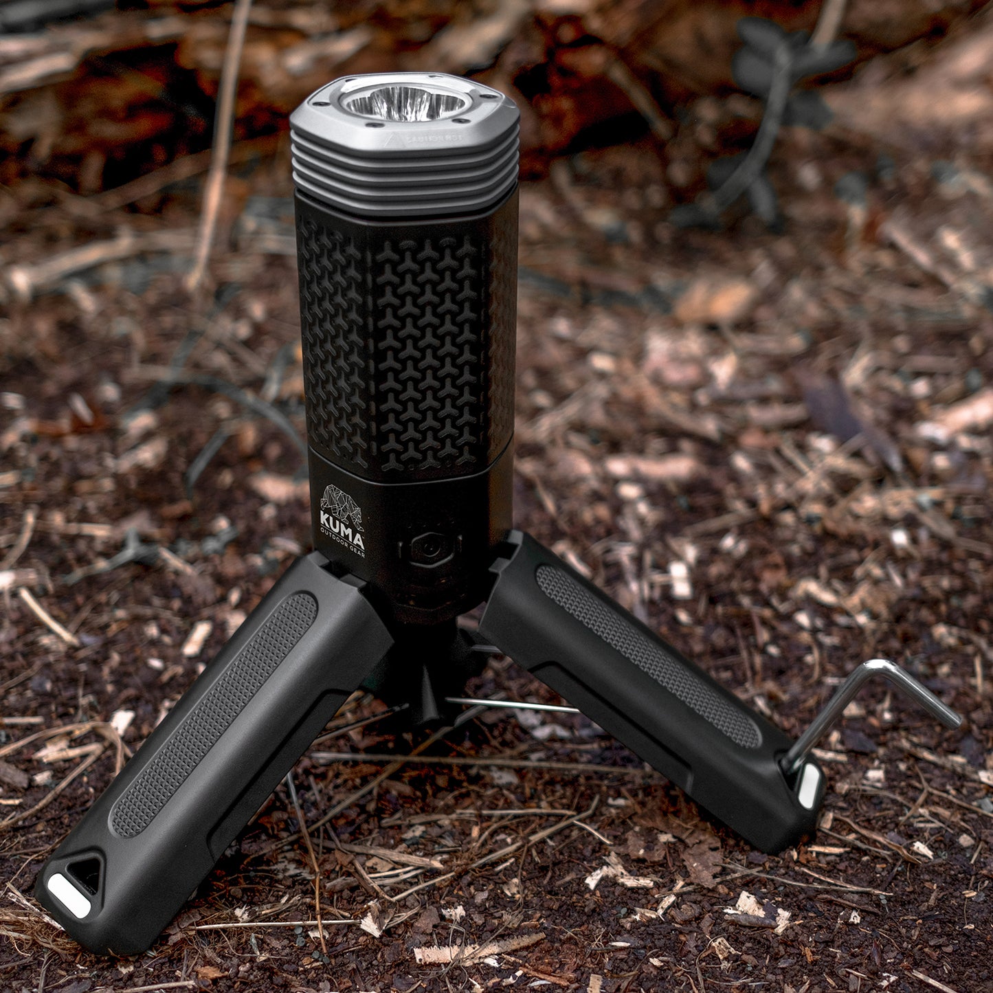 Black flashlight with tripod stand on a forest floor